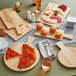 An Acopa light oak faux wood melamine serving board with a slice of pizza on it.