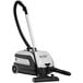 A Nilfisk canister vacuum with a black handle and white wheels on a white background.