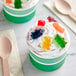 A green container of Kervan 12-Color Gummy Bears on a white surface with a green gummy bear.