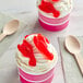 Two cups of ice cream with Kervan Gummy Lobsters on top on a table with a spoon.