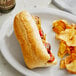 A sandwich and chips on a plate with a Turano 6" Sliced French Roll.