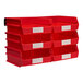 A red plastic wall storage system with white labels holding Triton Products red bins.