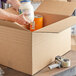 A man putting a container of milk into a Lavex Kraft shipping box.