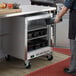 A man opening a Beverage-Air undercounter freezer with black drawers.