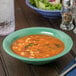 A bowl of soup and a bowl of salad on a wood table.