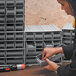 A person installing a Quantum gray drawer in a cabinet.