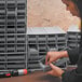 A person installing a Quantum gray high impact polystyrene drawer in a cabinet.
