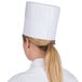 A woman wearing a white Royal Paper disposable chef hat.