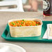 A World Centric rectangular compostable container filled with rice and peas on a tray.