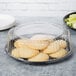 A WNA Comet clear plastic dome lid covering a plate of food and cookies.