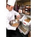 A chef using a white Rubbermaid ingredient bin to pour food into a bowl.