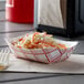 A red check paper food tray with coleslaw and carrots.