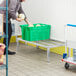 A man in a warehouse uses a Regency aluminum dunnage rack to hold green plastic bins of melons.