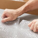 A person's hand cutting Pregis bubble wrap.