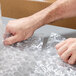 A person's hands holding a piece of Pregis bubble wrap.