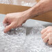 A person holding a box of Pregis bubble wrap.