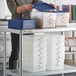 A woman holding a blue lid over a Choice translucent plastic container.