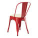 A Lancaster Table & Seating red metal cafe chair with white cushion.