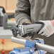 A person uses a Genesis 3" cut-off tool to cut a piece of wood.