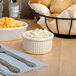 A table with Tuxton eggshell fluted ramekins filled with macaroni and cheese and coleslaw.