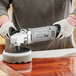 A person using a Genesis sander/polisher to clean a wooden surface.