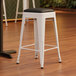 A Lancaster Table & Seating Pearl White Backless Counter Height Stool with Black Vinyl Cushion.