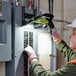 A woman wearing a hard hat and gloves using a PowerSmith LED work light.