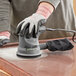 A person using a Genesis circular sander on a countertop.