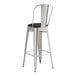 A Lancaster Table & Seating metal cafe barstool with black cushion.