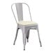 A Lancaster Table & Seating gray metal chair with a white cushion.