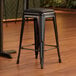 A Lancaster Table & Seating black backless counter height stool with black cushion.