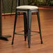 A Lancaster Table & Seating black backless counter height stool with a white cushion.