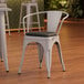 A Lancaster Table & Seating gray metal chair with black vinyl cushion.