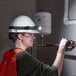 A woman wearing a hard hat and gloves working on a pipe with a PowerSmith LED headlamp.