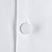 A close up of a white Chef Revival long sleeve chef coat with a button.