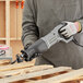 A person using a Genesis variable speed reciprocating saw to cut wood.