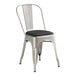 A Lancaster Table & Seating metal chair with black vinyl cushion on a white surface.
