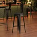 A Lancaster Table & Seating black barstool with a black cushion.