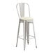 A Lancaster Table & Seating metal barstool with a white cushion.