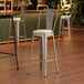 A Lancaster Table & Seating barstool with a white vinyl cushion on a wood floor.