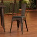 A Lancaster Table & Seating brown metal cafe chair with black vinyl cushion.