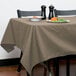 A table with a beige Intedge tablecloth and a plate of food on it.