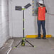 A man in a hard hat uses a PowerSmith Voyager work light in a garage.