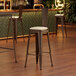 A Lancaster Table & Seating copper barstool with a white cushion on a wood floor.