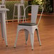 A Lancaster Table & Seating white metal chair with a black cushion on a table.