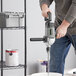 A man using a Genesis electric drill to mix something in a bucket.