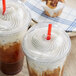 Two plastic cups of iced coffee with clear plastic dome lids and straws.