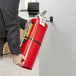 A person holding a Badger Advantage 18 lb. fire extinguisher on a wall.