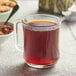 A glass mug of Davidson's Organic Earl Grey Red Herbal tea with a spoon and crackers.