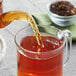 Davidson's Organic Decaf Spiced Peach Loose Leaf Tea being poured into a glass cup.